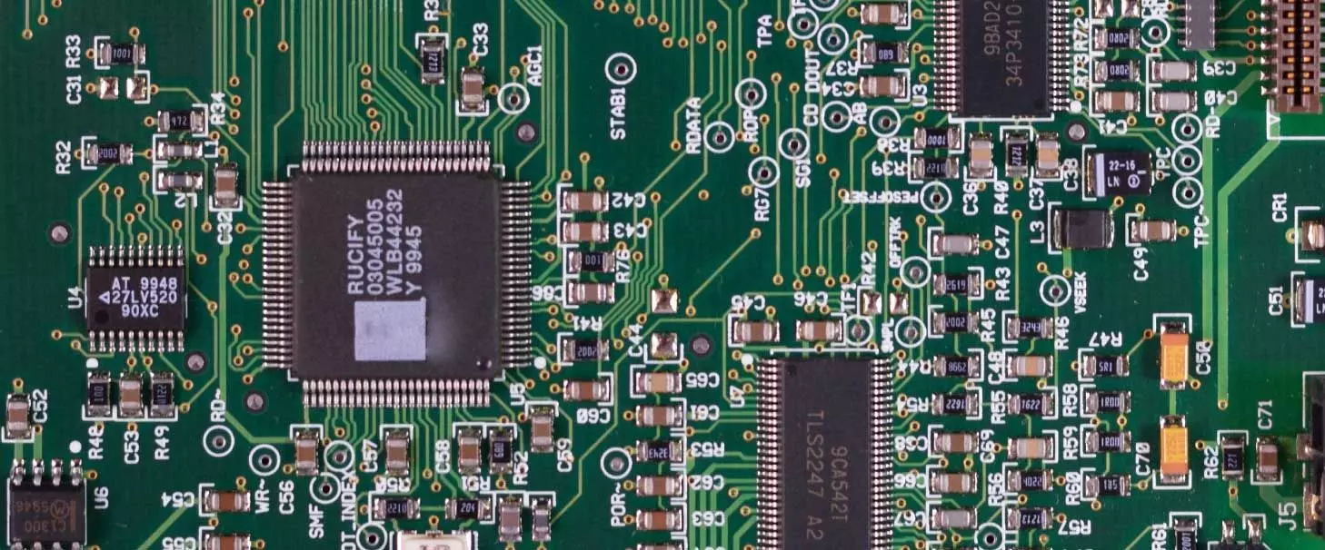 A close-up image of a circuit board showing microchips and various types of capacitors
