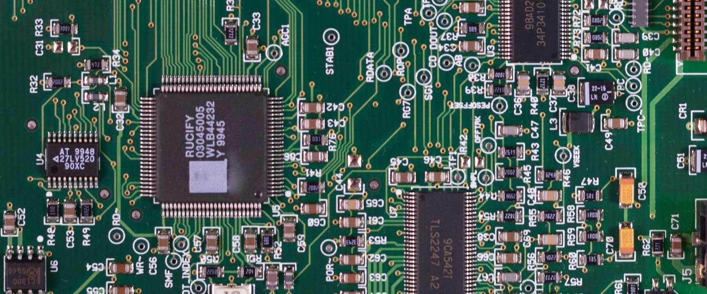 A close-up image of a circuit board showing microchips and various types of capacitors
